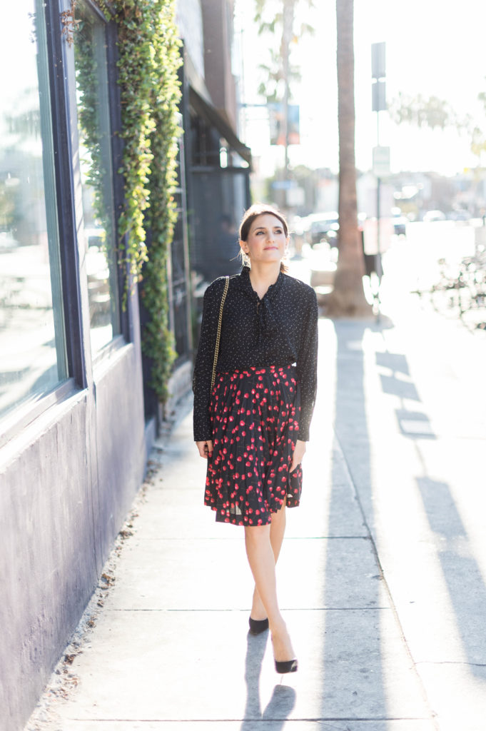 Lifestyle and corporate blogger Amanda Warsavsky wearing a J. Crew cherry skirt and a Banana Republic black bow blouse and Gucci bag