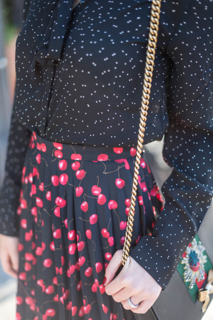 Lifestyle and corporate blogger Amanda Warsavsky wearing a J. Crew cherry skirt and a Banana Republic black bow blouse and Gucci bag