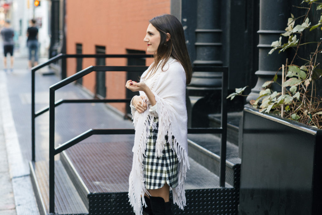 Lifestyle and corporate blogger That Pencil Skirt wearing a J. Crew check mini skirt, Stuart Wetizman Over the Knee boots and a fringe scarf