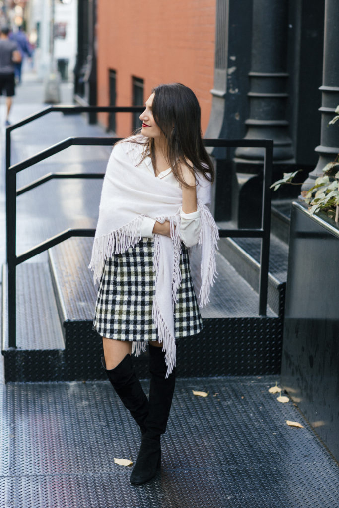 Lifestyle and corporate blogger That Pencil Skirt wearing a J. Crew check mini skirt, Stuart Wetizman Over the Knee boots and a fringe scarf