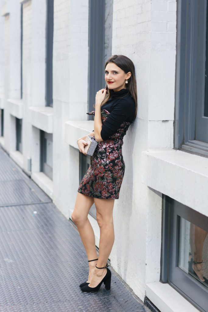 Lifestyle and Corporate Blogger Amanda Warsavsky wearing a strapless holiday dress, black turtleneck, black pumps with an ankle strap and Edie Parker glitter bag