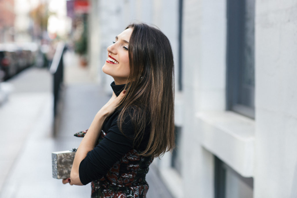 Lifestyle and Corporate Blogger Amanda Warsavsky wearing a strapless holiday dress, black turtleneck and Edie Parker glitter bag