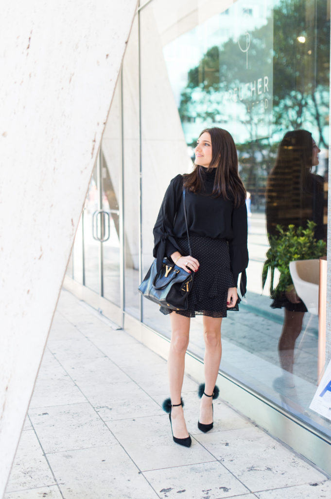 Lifestyle and workwear blogger That Pencil Skirt wearing a Club Monaco black ruffle skirt and a black turtleneck with a black off the shoulder top layered over