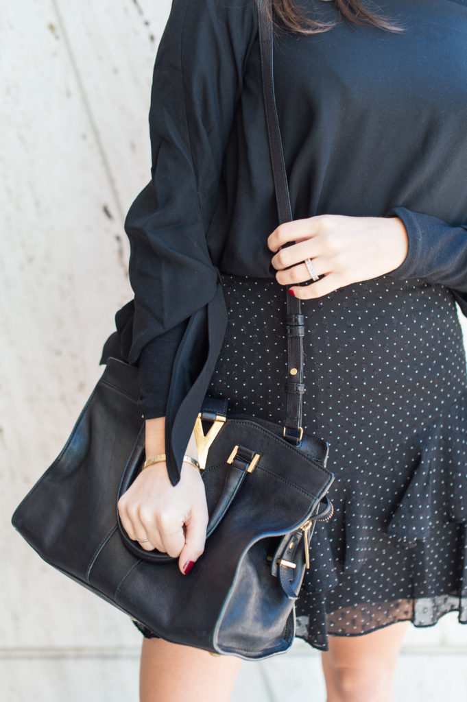Lifestyle and workwear blogger That Pencil Skirt wearing a Club Monaco black ruffle skirt and a black turtleneck with a black off the shoulder top layered over. With a Saint Laurent bag.