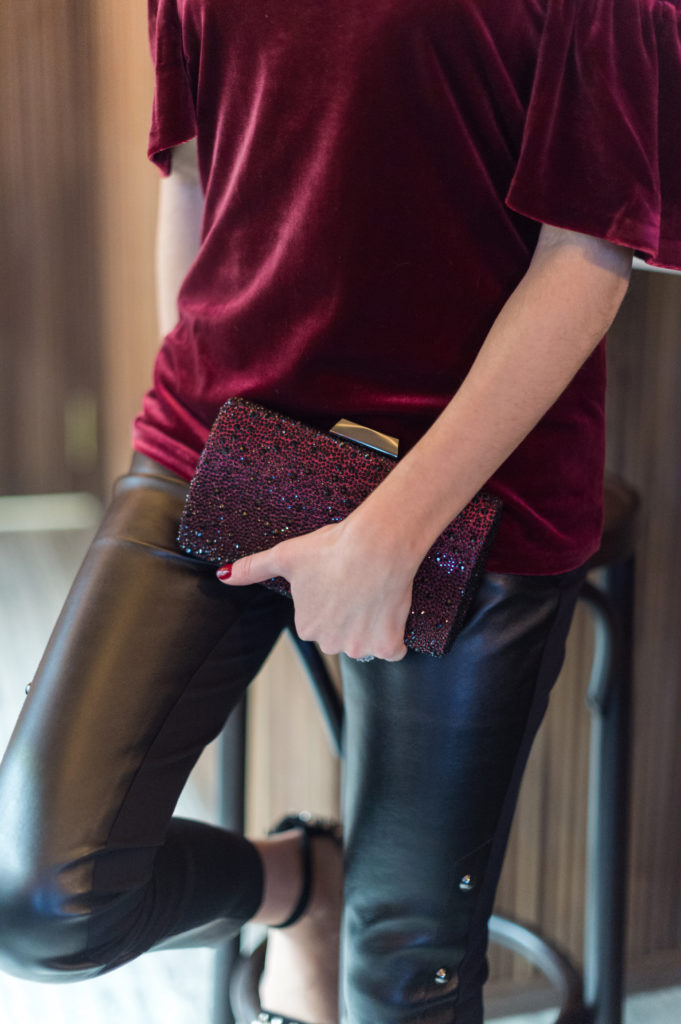 That Pencil Skirt, a lifestyle and work style blogger, wearing vegan leather pants, a burgundy velvet off the shoulder top and a burgundy rhinestone clutch from the White House Black Market holiday collection