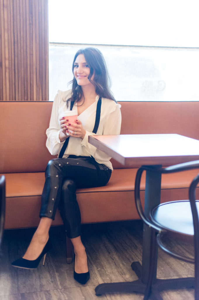 That Pencil Skirt, a lifestyle and work style blogger, wearing vegan leather pants, and a white blouse with a black velvet tie and black velvet pumps from the White House Black Market holiday collection