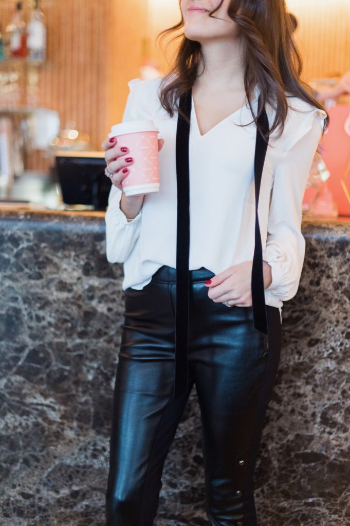 That Pencil Skirt, a lifestyle and work style blogger, wearing vegan leather pants, and a white blouse with a black velvet tie from thefrom the White House Black Market holiday collection