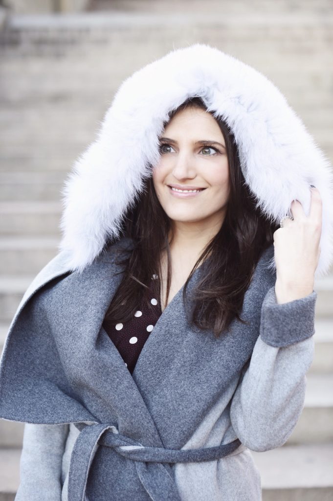 That Pencil Skirt, a lifestyle and work wear blogger, wearing a Soia and Kyo gray wrap coat with a fur hood, and Jimmy Choo gray sock ankle boots