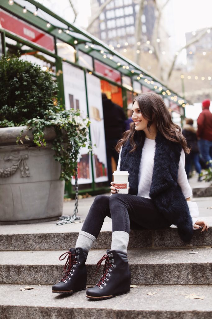 Lifeistyle blogger That Pencil Skirt wearing Sorel boots, cashmere socks. a black fur vest and an Aqua sweater all bought at Bloomingdales