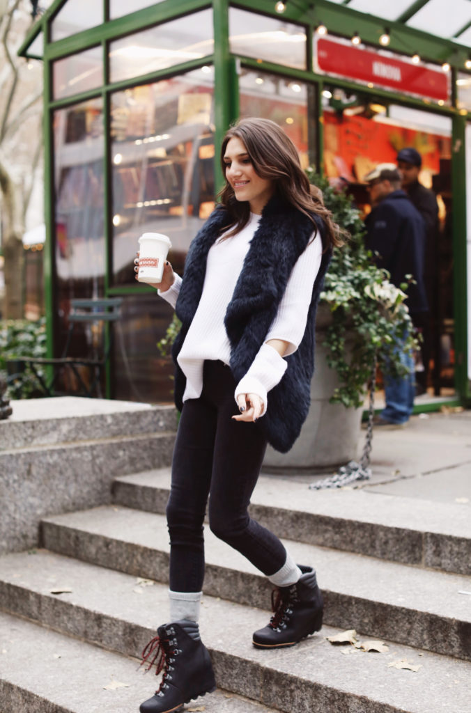 Lifeistyle blogger That Pencil Skirt wearing Sorel boots, cashmere socks. a black fur vest and an Aqua sweater all bought at Bloomingdales