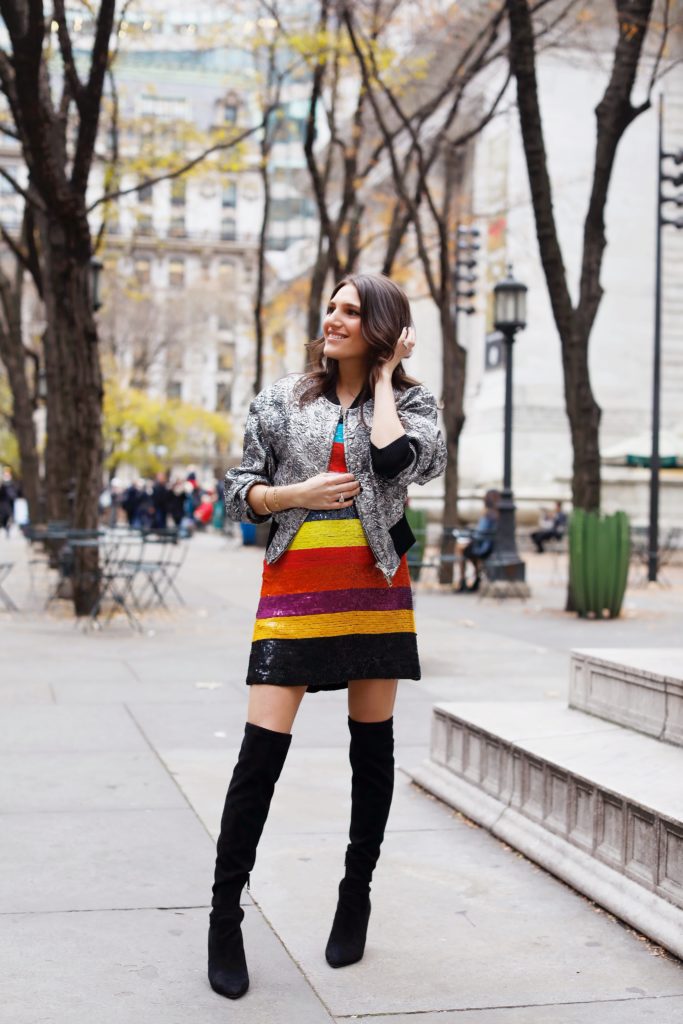 That Pencil Skirt, a fashion blogger, wearing an Alice and Olivia striped sequin color mini dress, with a Philip Lim silver embroidered bomber jacket and over the knee black suede boots
