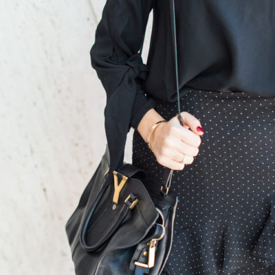 Lifestyle and workwear blogger That Pencil Skirt wearing a Club Monaco black ruffle skirt and a black turtleneck with a black off the shoulder top layered over. With a Saint Laurent bag.